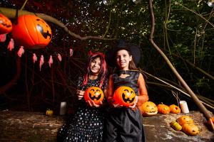 two girls dressed in costumes for halloween holding pumpkins