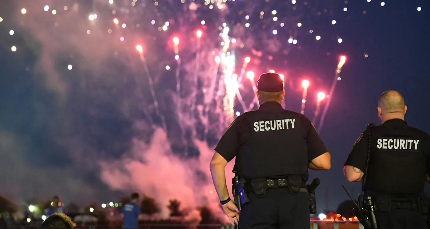 two security officers keeping watch with fireworks in the background