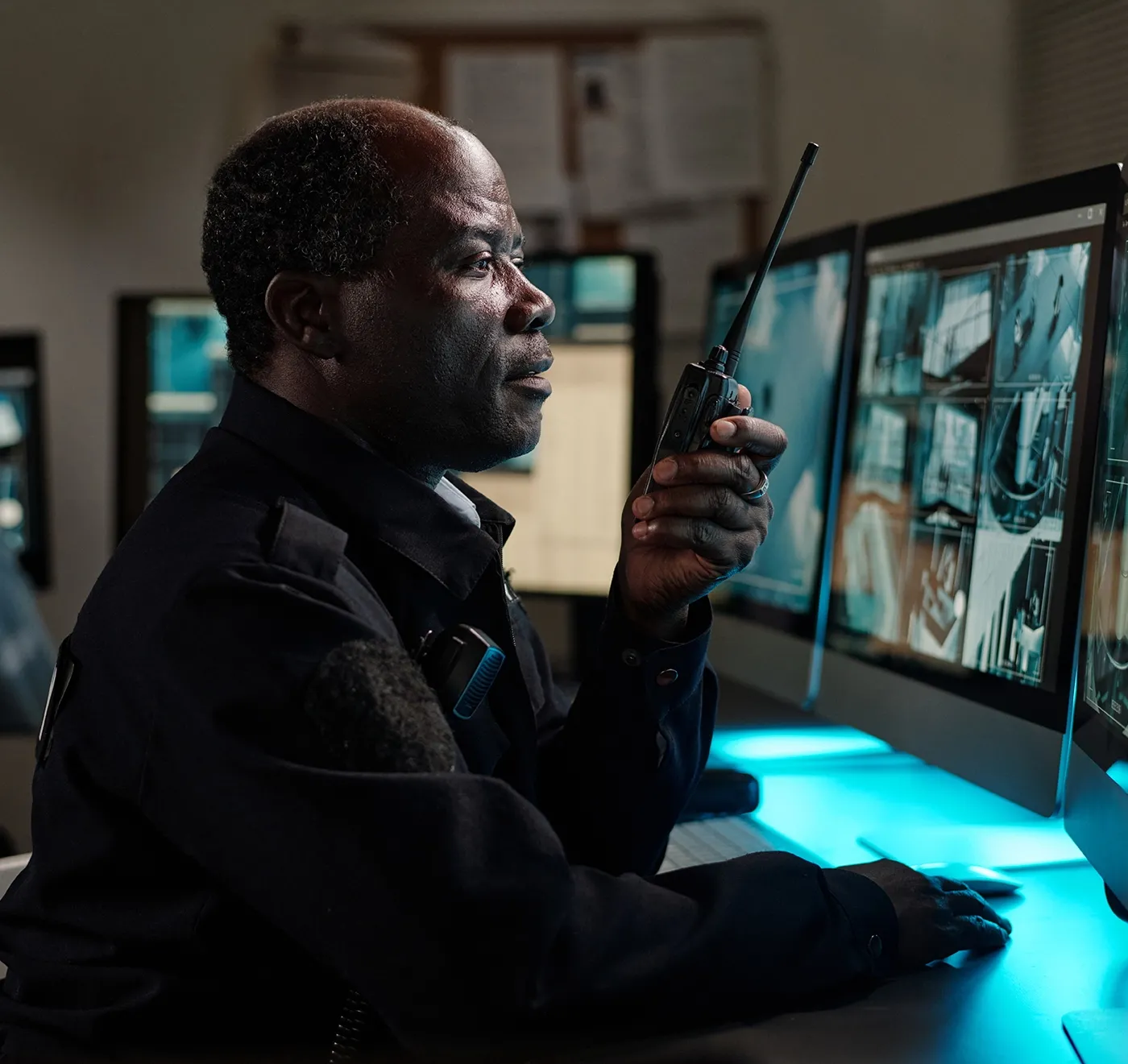 officer watching remote monitoring screens, talking on radio