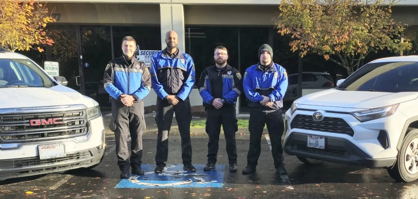 four security officers standing between two patrol vehicles