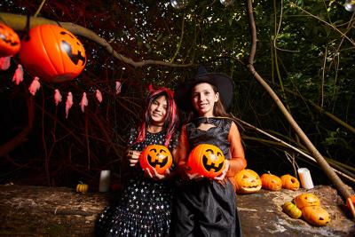 two girls dressed in costumes for halloween holding pumpkins